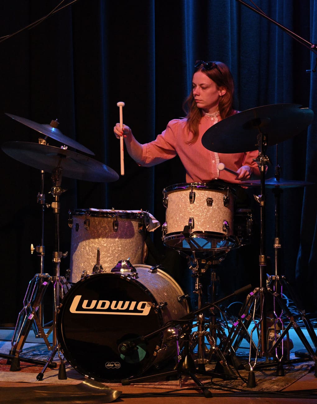 Jen Playing drums in a pink shirt