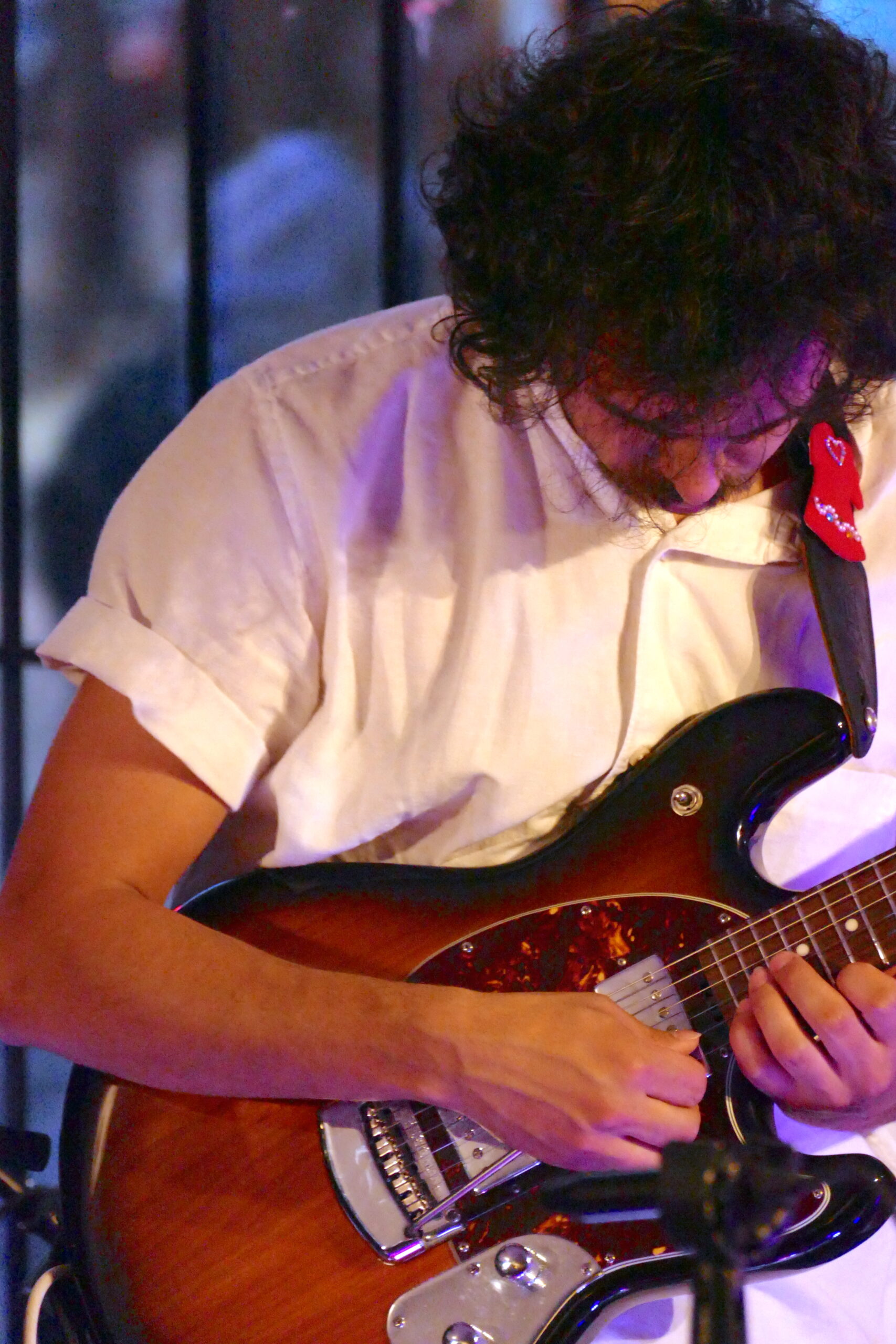 Matthew looking down at his guitar in a white shirt