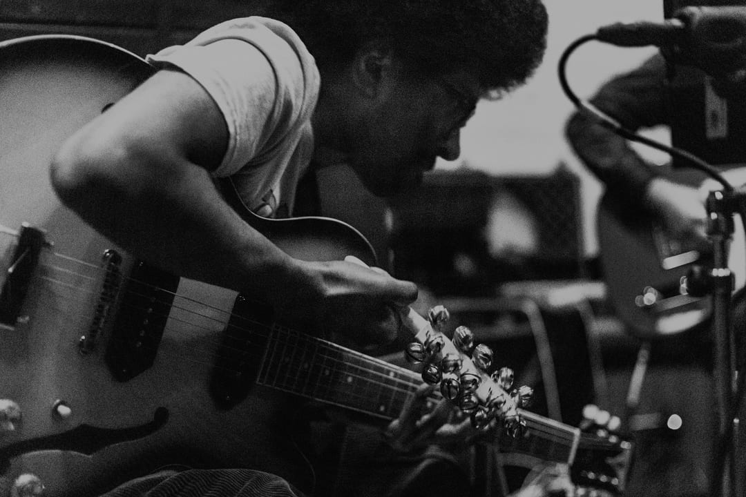 Mustafa playing guitar with bells in black and white image